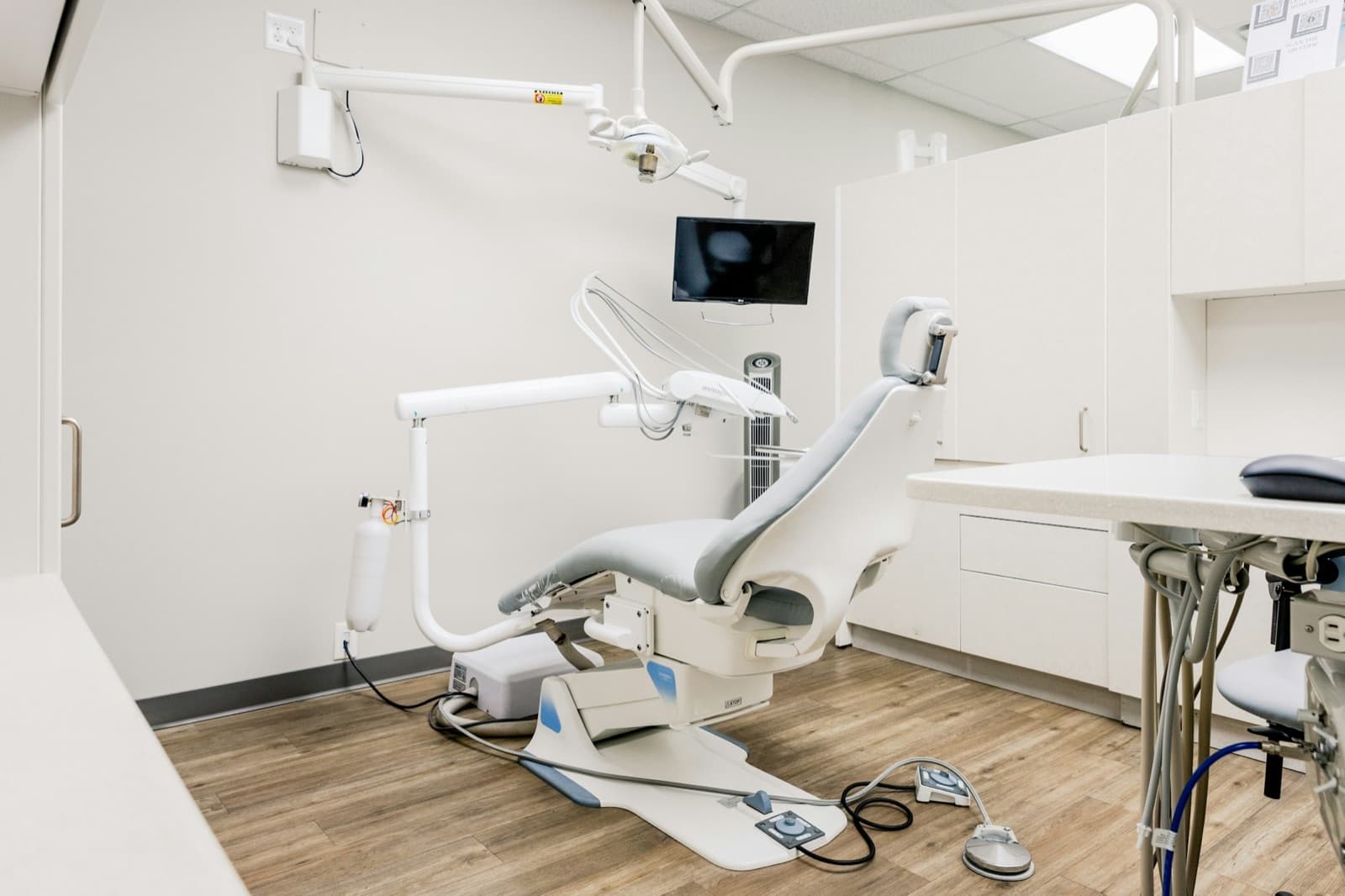 A bright, modern treatment room at Aster Dental with a reclined chair and pale wood floor